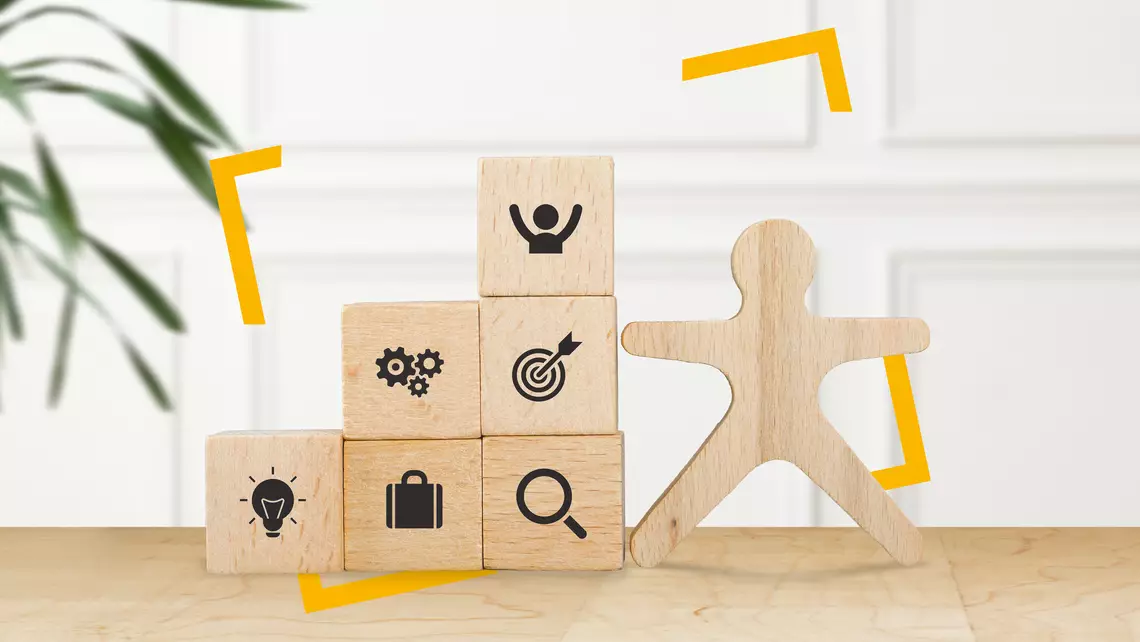 Plusieurs petits cubes en bois avec des pictogrammes sont positionnés à côté d'un personnage joyeux